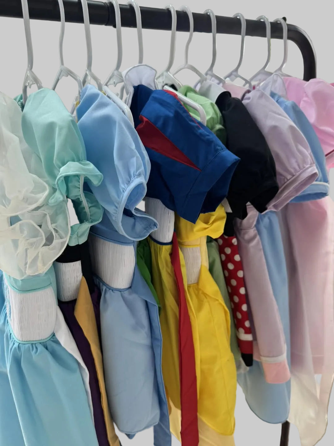 Colorful baby rompers on hangers against a neutral background